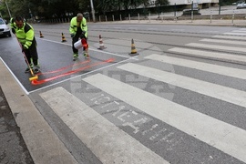 Workers are putting a specialty road dressing designed to slow down cars as they approach a pedestrian crossing in Sofia