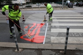 Workers are putting a specialty road dressing designed to slow down cars as they approach a pedestrian crossing in Sofia