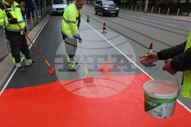 Workers are putting a specialty road dressing designed to slow down cars as they approach a pedestrian crossing in Sofia