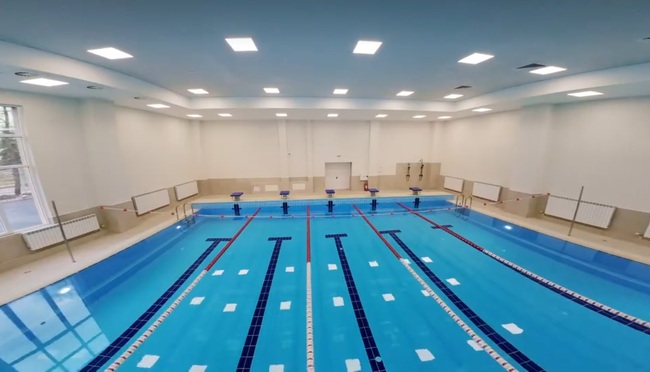 Родител напръска със спрей спасител, работещ към закрит плувен басейн в Перник